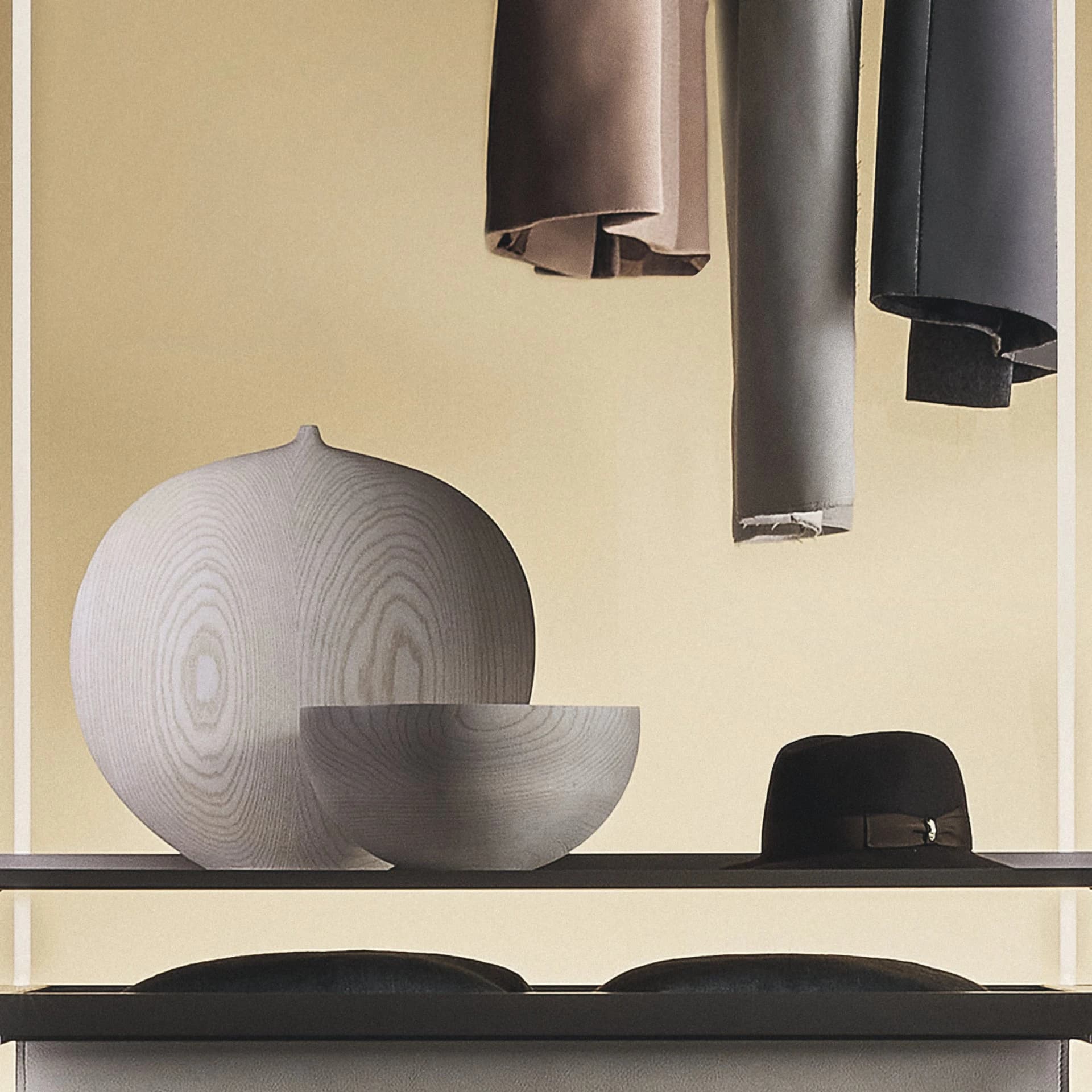 A shelf detail showing turned timber vessels and a felt hat under warm light